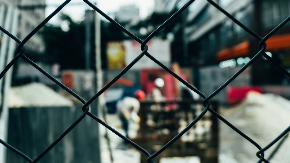 Chain-link fence with construction activity beyond it